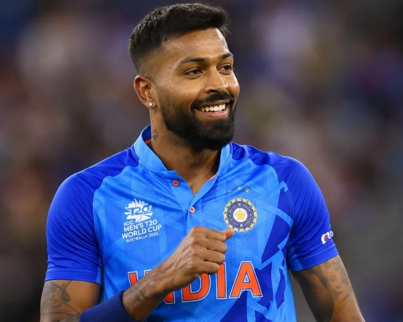 Hardik Pandya smiling on the cricket field in India's blue jersey during an international match.